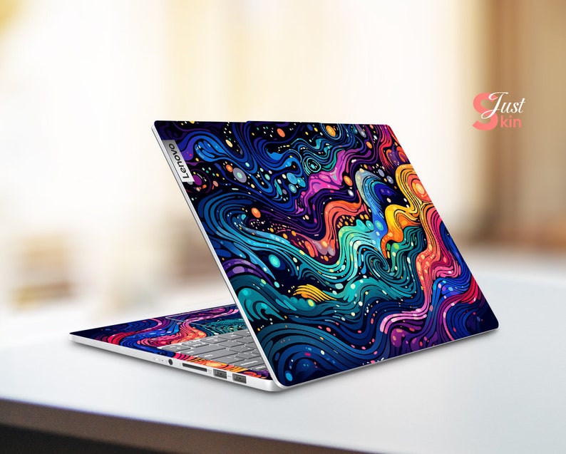 Puede incluir: Un port&aacute;til Lenovo con una llamativa funda abstracta con patrones ondulados en tonos azules, morados, naranjas y amarillos. La funda cubre la tapa y el &aacute;rea del teclado, creando un dise&ntilde;o cohesivo. El texto "Just Skin" es visible.
