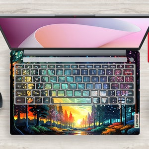 K&ouml;nnte beinhalten: Ein Laptop mit einem farbenfrohen Waldmotiv und Sonnenuntergang auf der Tastatur und dem Trackpad. Das Design zeigt eine Vielzahl von Farben, darunter Gr&uuml;n, Blau, Lila und Gelb. Der Laptop ist ge&ouml;ffnet und der Bildschirm ist ausgeschaltet. Der Laptop steht auf einer Holzoberfl&auml;che.