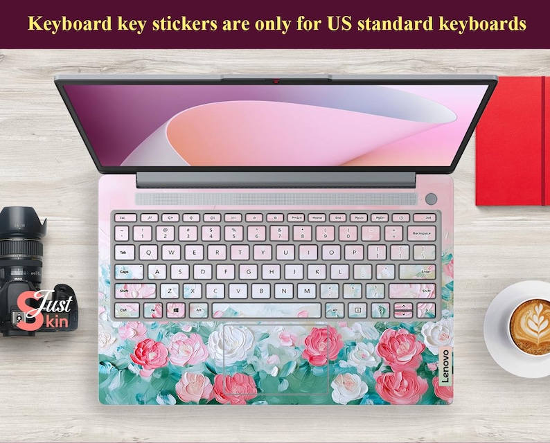 Peut inclure: Un ordinateur portable avec un autocollant de clavier floral. L'autocollant pr&eacute;sente des fleurs roses, blanches et vertes sur un fond rose clair. L'ordinateur portable est ferm&eacute; et l'&eacute;cran affiche un fond rose et blanc.