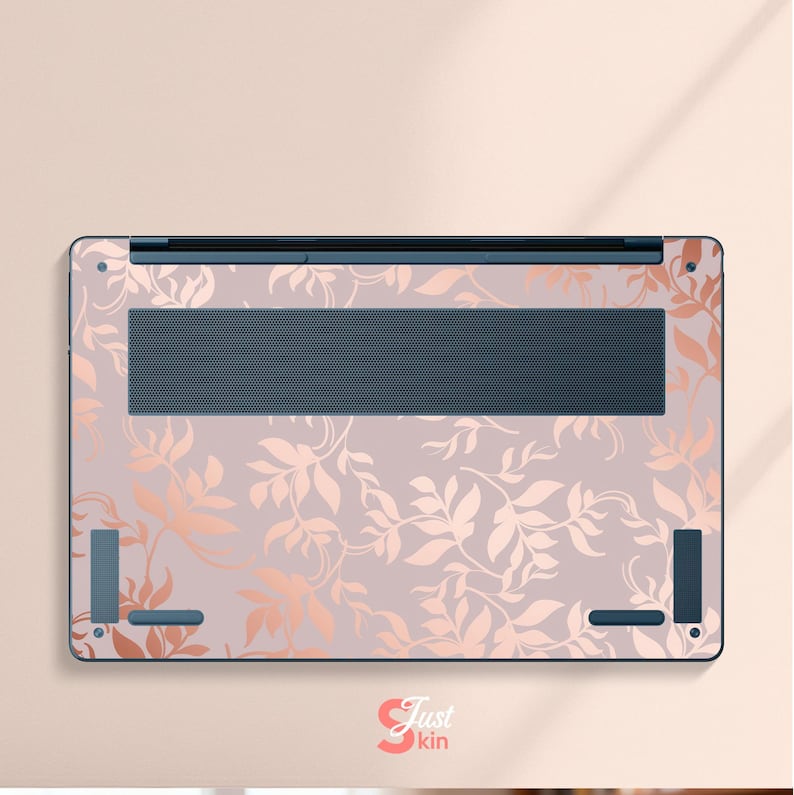 May include: Laptop skin featuring a floral design in rose gold and light pink. The skin covers the bottom of the laptop, with cutouts for the vent and feet. The design includes a repeating pattern of leaves and vines.
