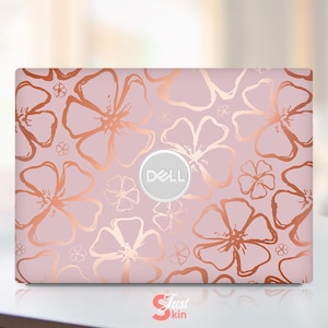 May include: A Dell laptop skin featuring a pink background with a repeating pattern of copper-colored floral designs. The Dell logo is centered on the skin. The words "Just Skin" are at the bottom.