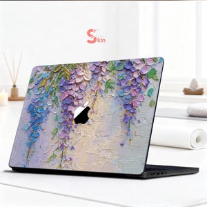 K&ouml;nnte beinhalten: Laptop-Skin mit einem floralen Design aus kaskadenartigen lila, blauen und gr&uuml;nen Blauregenbl&uuml;ten. Das Kunstwerk hat ein strukturiertes, gemaltes Aussehen. Das Apple-Logo ist sichtbar. Die Skin ist auf einem schwarzen Laptop angebracht.