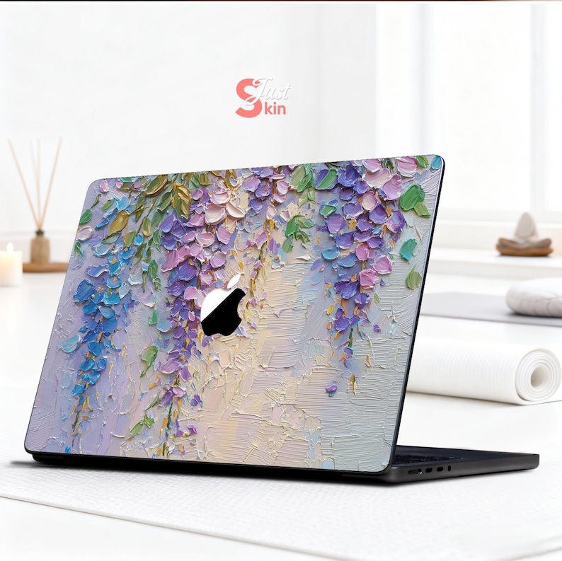 K&ouml;nnte beinhalten: Laptop-Skin mit einem floralen Design aus kaskadenartigen lila, blauen und gr&uuml;nen Blauregenbl&uuml;ten. Das Kunstwerk hat ein strukturiertes, gemaltes Aussehen. Das Apple-Logo ist sichtbar. Die Skin ist auf einem schwarzen Laptop angebracht.