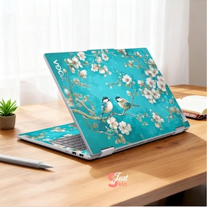 Op de afbeelding: Een turquoise laptop skin met een bloemen- en vogelontwerp. De laptop is open en toont een tak met witte bloemen en twee vogels. Het woord "YOGA" is zichtbaar. Op een houten bureau.