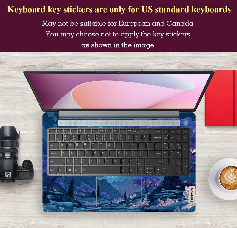 K&ouml;nnte beinhalten: Ge&ouml;ffnetes Laptop mit einer Tastaturfolie mit einem blauen und violetten Landschaftsdesign. Die Tastatur hat schwarze Tasten. Das Bild enth&auml;lt eine Kamera, ein rotes Notizbuch und eine Tasse Kaffee. Der Text besagt, dass die Tastaturaufkleber nur f&uuml;r US-Tastaturen geeignet sind.