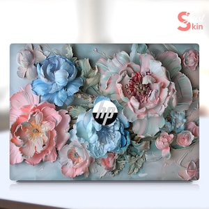 Puede incluir: Una piel para portátil con un diseño floral con flores rosas, azules y blancas. Las flores están pintadas en un estilo realista y parecen ser tridimensionales. La piel también presenta el logotipo de HP en el centro.