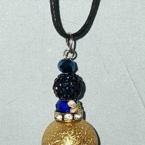 May include: A set of three ceramic mugs with a speckled, matte finish. The mugs are in shades of cream, light brown, and dark brown. Each mug has a simple, minimalist design and a rounded handle.