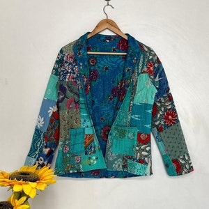 May include: A blue patchwork jacket with a floral print. The jacket has a collar and long sleeves. The fabric is quilted and has a variety of different patterns.