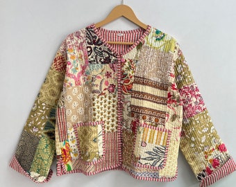 Può includere: Una giacca trapuntata patchwork con chiusura a bottone. La giacca è realizzata con diversi tessuti in tonalità crema, rosa, verde e marrone. La giacca ha una stampa floreale e paisley.