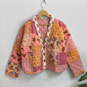 May include: A pink quilted jacket with a patchwork design featuring floral and animal prints. The jacket has a button-up front and long sleeves.