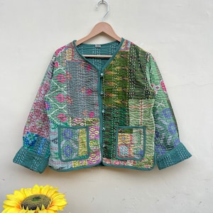May include: A green quilted jacket with a patchwork design. The jacket has a button closure and two pockets.
