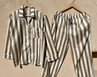 May include: A striped pajama set with a long-sleeved shirt and pants. The shirt has a button-up front and a pocket on the left chest. The pants have a drawstring waistband.