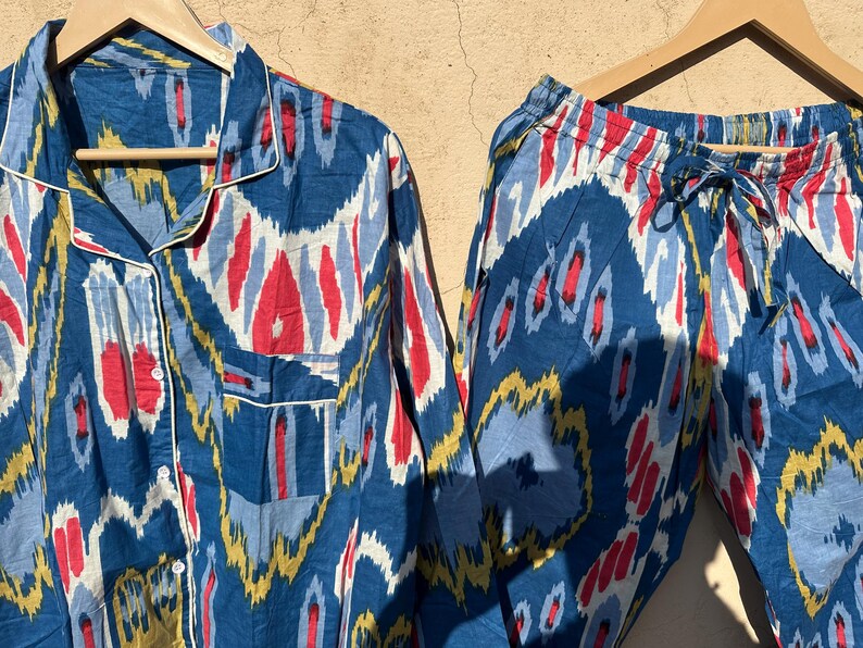 May include: A blue and white patterned pajama set with a long-sleeved shirt and pants. The pattern features abstract shapes in shades of blue, white, red, and yellow.
