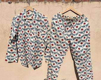 May include: A white pajama set with a red and blue floral print. The top has a button-down collar and long sleeves. The pants have an elastic waistband.