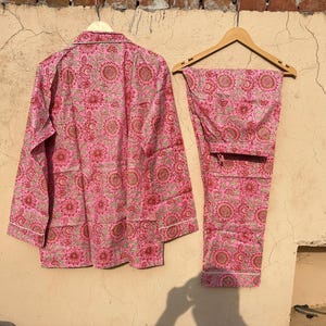 May include: A pink and green floral print pajama set with a long-sleeved top and pants.