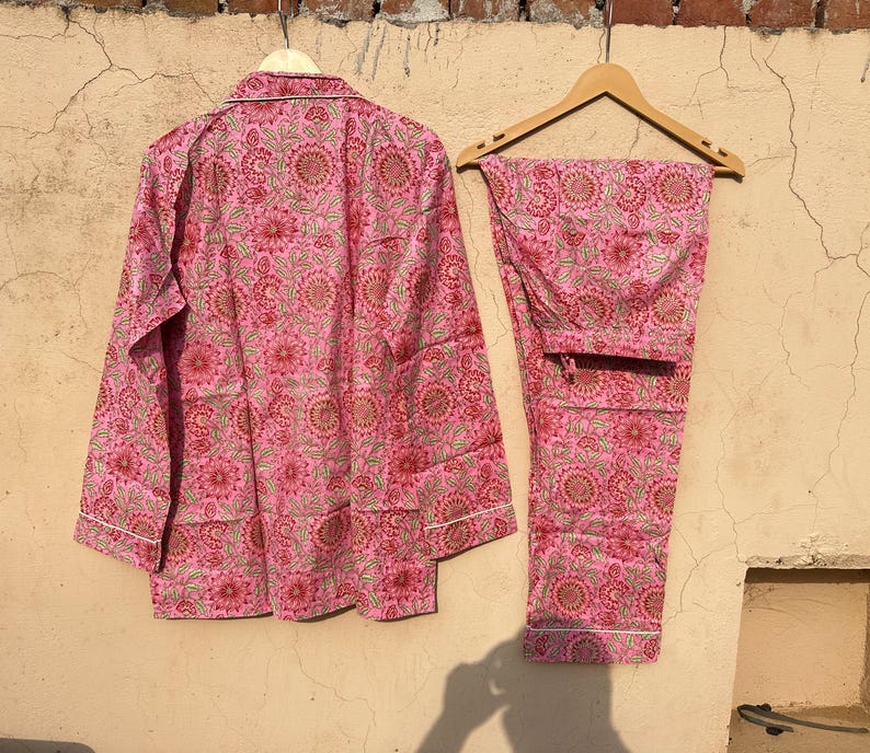 May include: A pink and green floral print pajama set with a long-sleeved top and pants.
