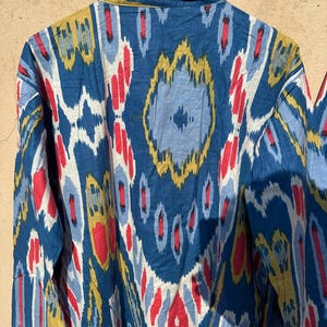 May include: A blue, red, yellow, and white patterned long-sleeve shirt with a button-up collar.