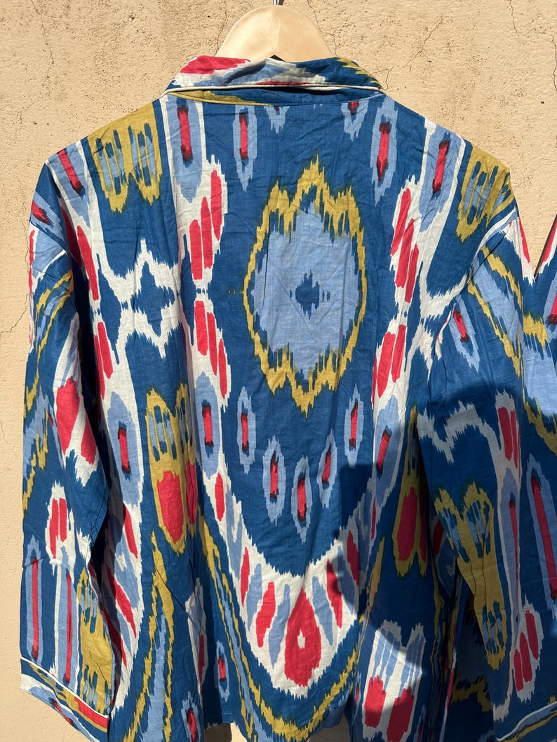 May include: A blue, red, yellow, and white patterned long-sleeve shirt with a button-up collar.
