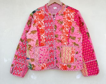 Può includere: Una giacca trapuntata rosa con un design a patchwork che presenta tigri, fiori e motivi geometrici. La giacca ha un colletto alla coreana, maniche lunghe e una chiusura con bottoni.