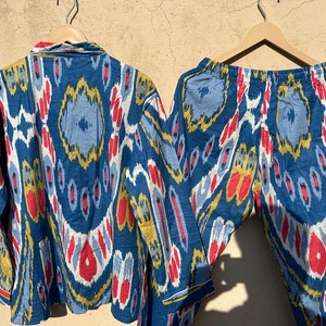 May include: A blue and white patterned pajama set with red and yellow accents. The top has a button-up closure and long sleeves. The pants have an elastic waistband.