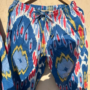 May include: Blue, red, and yellow patterned pants with an elastic waistband and a drawstring. The pants are made of a soft, lightweight fabric.