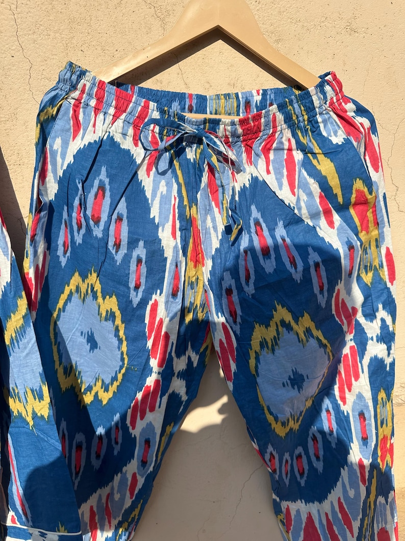 May include: Blue, red, and yellow patterned pants with an elastic waistband and a drawstring. The pants are made of a soft, lightweight fabric.