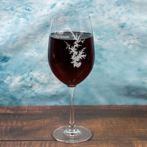 May include: A clear wine glass with a red wine inside. The glass is etched with the outline of a lake and the text "Lake Norman".