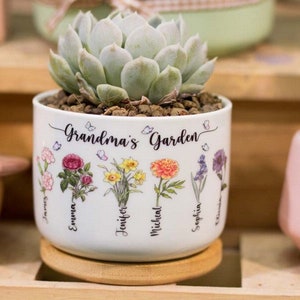 May include: White ceramic planter with a succulent plant and the text "Grandma's Garden" on the front. The planter has five flowers and names printed on the side.