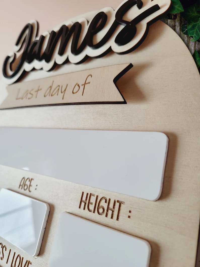 May include: A wooden growth chart with the name "James" in black lettering. The chart has a banner that says "Last day of" and includes spaces to record age and height.