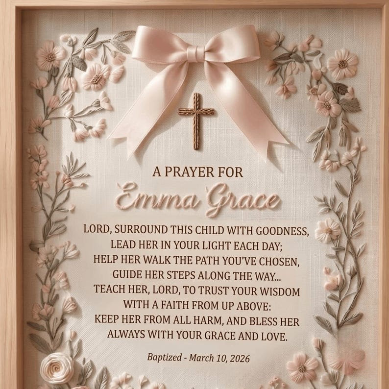 May include: A framed wall art piece featuring a light pink satin bow and a small brown cross centered above the text A PRAYER FOR Emma Grace. The prayer text is followed by the date Baptized - March 10, 2026, surrounded by floral embroidery.
