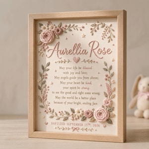 May include: A light wood framed wall art piece featuring cream fabric with pink floral embroidery and the text Aurellia Rose, a poem, and the date BAPTIZED SEPTEMBER 15TH, 2026. The design includes embroidered vines, leaves, and small stars.