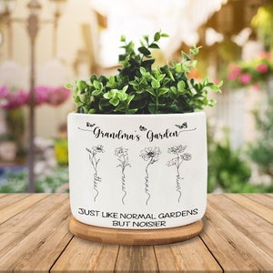 May include: White ceramic planter with the text "Grandma's Garden" and four stylised flowers with names written underneath. The planter has a wooden base and the text "Just like normal gardens but noisier" is written on the bottom.