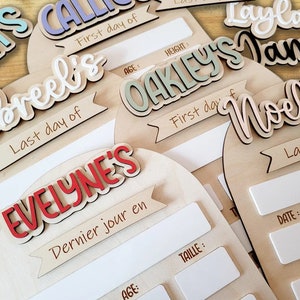 May include: Set of six wooden signs with white, black, and red lettering. Each sign has a name, "Jibreel's", "Oakley's", "Noella", "Evelyn's", "Laylah's", and "James", and a banner with the text "First day of" or "Last day of".