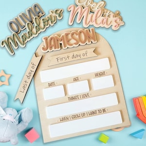 May include: A wooden growth chart with a light brown arch and white spaces to fill in with details about a child's first day and last day. The chart has the text "Last day of" and "First day of" on the left and right sides of the arch. The chart also has the text "Date", "Age", "Height", "Things I Love", and "When I grow up, I want to be".