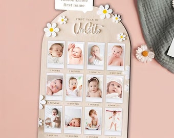 Puede incluir: Un marco de fotos de hitos para bebés de madera con el texto "FIRST YEAR OF" y el nombre "Violette". Cuenta con espacios para 12 fotos, con detalles de margaritas y el texto "customizable first name".