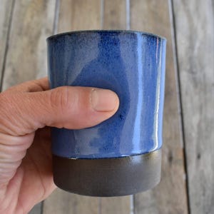 Peut inclure: Une tasse en c&eacute;ramique bleue avec un bord brun fonc&eacute;. La tasse est &eacute;maill&eacute;e et a un l&eacute;ger brillant.