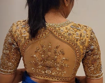 May include: A gold embroidered blouse with a sheer back panel. The embroidery features floral and leaf designs with gold beads and sequins.