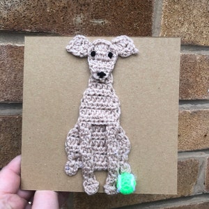 May include: A crocheted brown dog with black eyes and a green tennis ball.