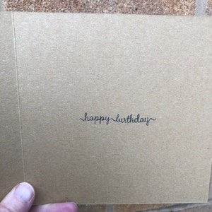 May include: A brown card with the text "happy birthday" written in black cursive.
