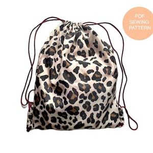 May include: A drawstring bag with a leopard print design. The bag is made of a soft, silky fabric and has a maroon drawstring.