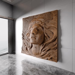 Könnte beinhalten: Eine Wandskulptur aus Holz, die ein Gesicht mit einem geschichteten 3D-Effekt darstellt. Die Skulptur besteht aus dünnen Holzstreifen, die in einem wellenförmigen Muster angeordnet sind. Das Gesicht ist teilweise von den Holzstreifen verdeckt, was ein Gefühl von Geheimnis und Intrige erzeugt.