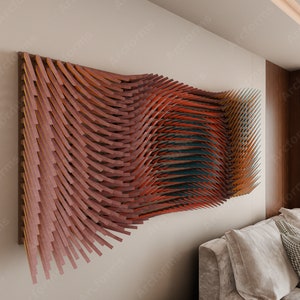 Puede incluir: Un sal&oacute;n moderno con una gran obra de arte de pared abstracta hecha de listones de madera en tonos marrones, rojos y azules. La obra de arte est&aacute; colgada en una pared de color beige claro. Un sof&aacute; beige con almohadas est&aacute; en primer plano.