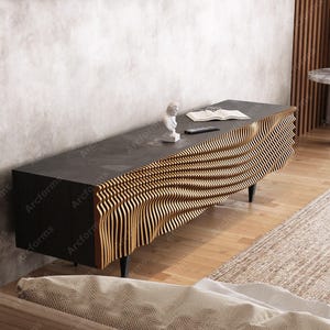 May include: A modern black and gold TV stand with a unique wavy wood design. The stand has four black legs and a smooth black top.
