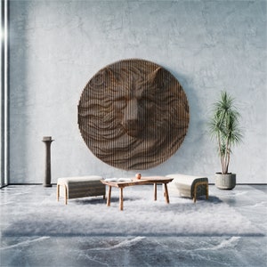 May include: A modern living room interior with a large, round, wooden wall sculpture featuring a geometric pattern. Two light-colored ottomans and a wooden coffee table are placed in front of the sculpture, with a potted plant in the background.
