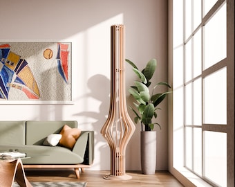 May include: A wooden floor lamp with a unique, geometric design. The lamp is made of natural wood and has a warm, inviting feel. The lamp is standing in a living room with a green sofa and a potted plant.