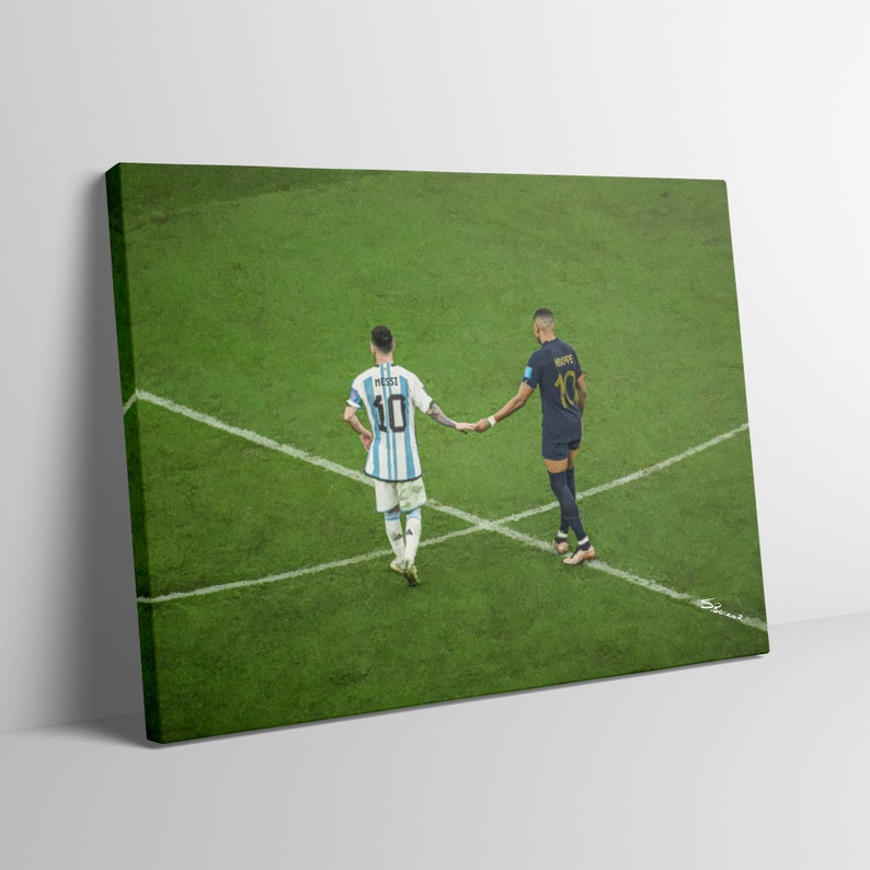 May include: Two soccer players, one in a light blue and white jersey with the number 10 and the name "MESSI" on the back, and the other in a dark blue jersey with the number 10 and the name "MBAPPE" on the back, shake hands on a green soccer field.