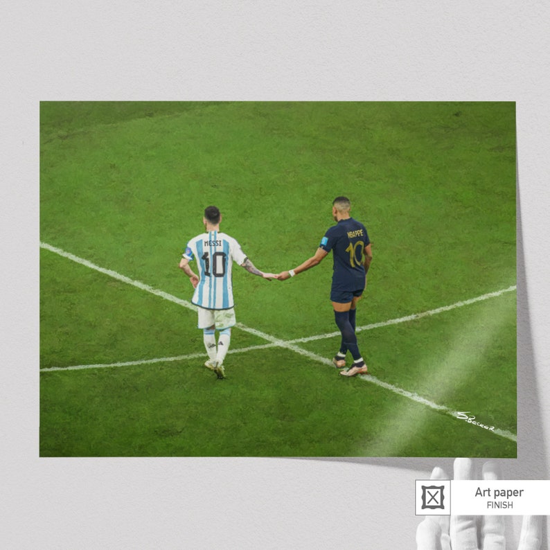 May include: Two soccer players, one in a blue and white jersey with the name "Messi" and number "10" on the back, and the other in a dark blue jersey with the name "Mbappe" and number "10" on the back, shake hands on a green soccer field.
