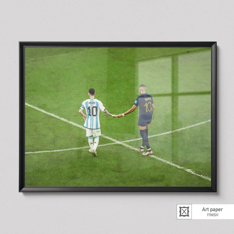 May include: Two soccer players, one in a light blue and white jersey with the number 10 and the name "MESSI" on the back, and the other in a dark blue jersey with the number 10 and the name "MBAPPE" on the back, shake hands on a green soccer field.