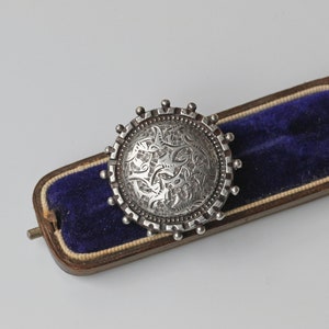Broche antiguo de estética victoriana con detalles grabados, en plata de ley.