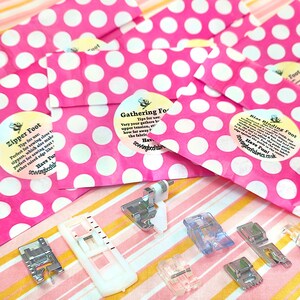 May include: A set of sewing machine feet in pink polka dot bags. The feet include a zipper foot, a gathering foot, a bias binding foot, and a 1/4 inch foot. The bags have labels with the text "Have Fun!" and "sewingbeefabrics.co.uk".